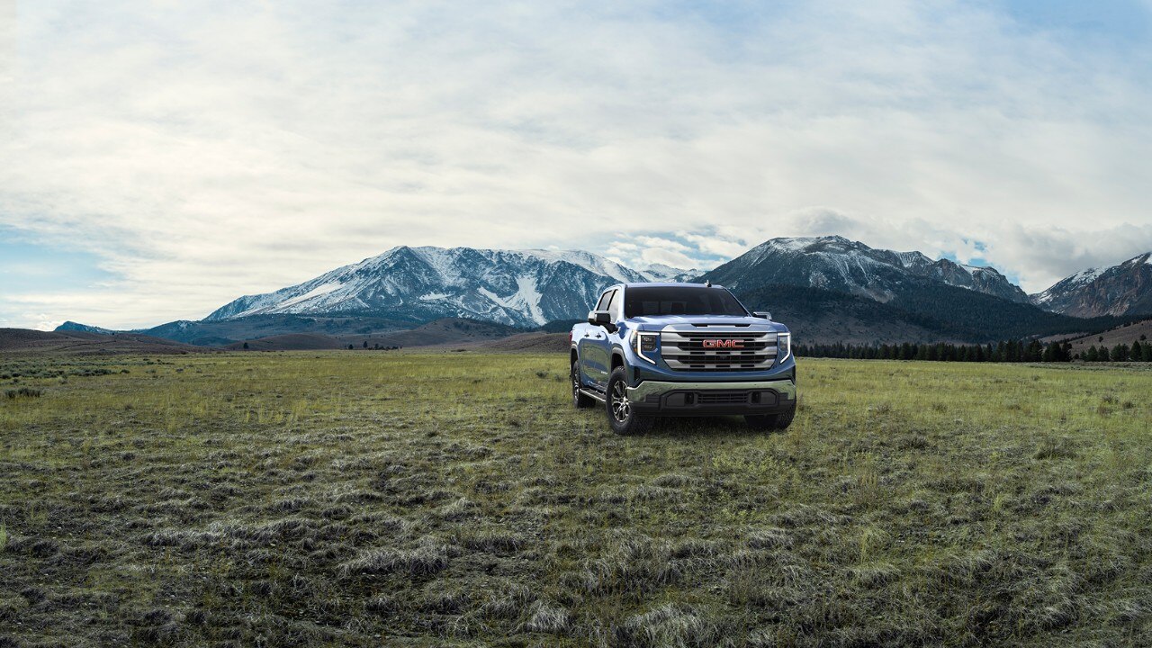 Onyx Black GMC Sierra 1500 SLE parked in an open field with mountains in the background.