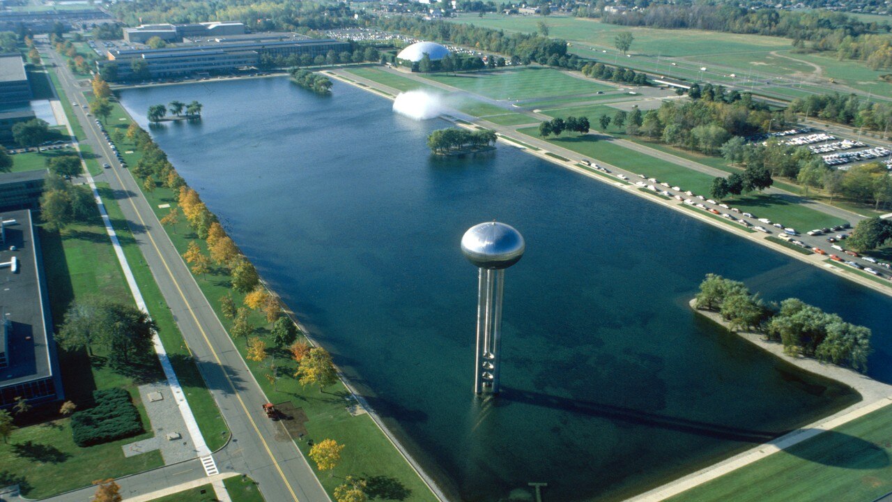 Aerial view of the General Motors Technical Center, featuring a water tower, large reflecting pool, and modernist buildings.