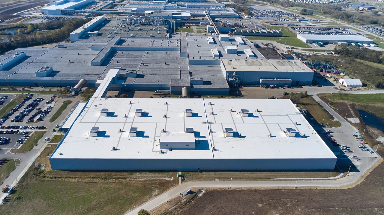 Aerial view of a GM automotive manufacturing plant with expansive factory buildings and adjacent parking lots.