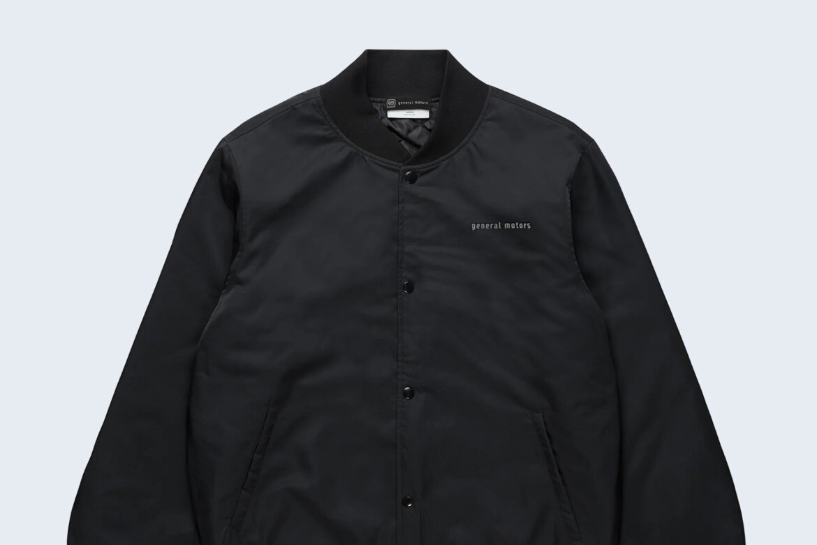 Black Collegiate Bomber Jacket With General Motors Text on Chest with Button-Up Front, Side Pickets, and Ribbed Cuffs.